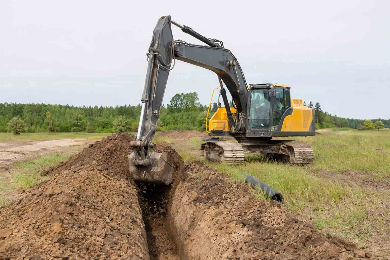 excavator using a trenching bucket for drainage line digging work.