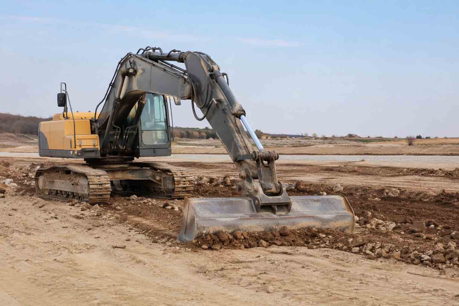 excavator using a grading bucket for site clean-up and surface finishing work
