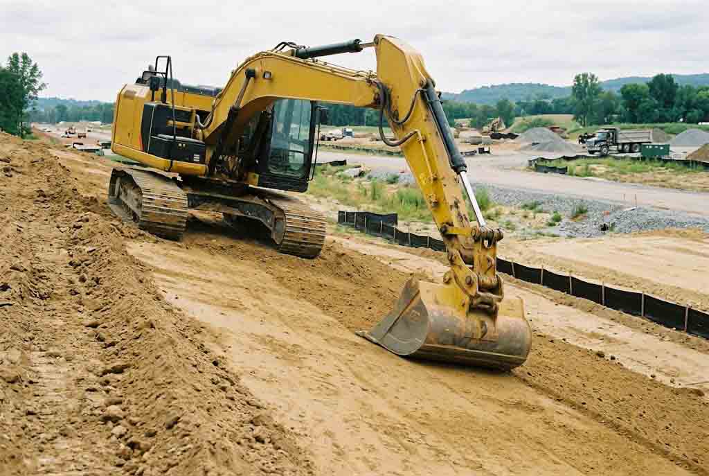 excavator using a grading bucket for controlled slope finishing work